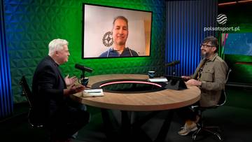 Dwóch mężczyzn rozmawia przy okrągłym stole w studiu telewizyjnym, podczas gdy na dużym ekranie za nimi wyświetla się obraz kolejnego mężczyzny.