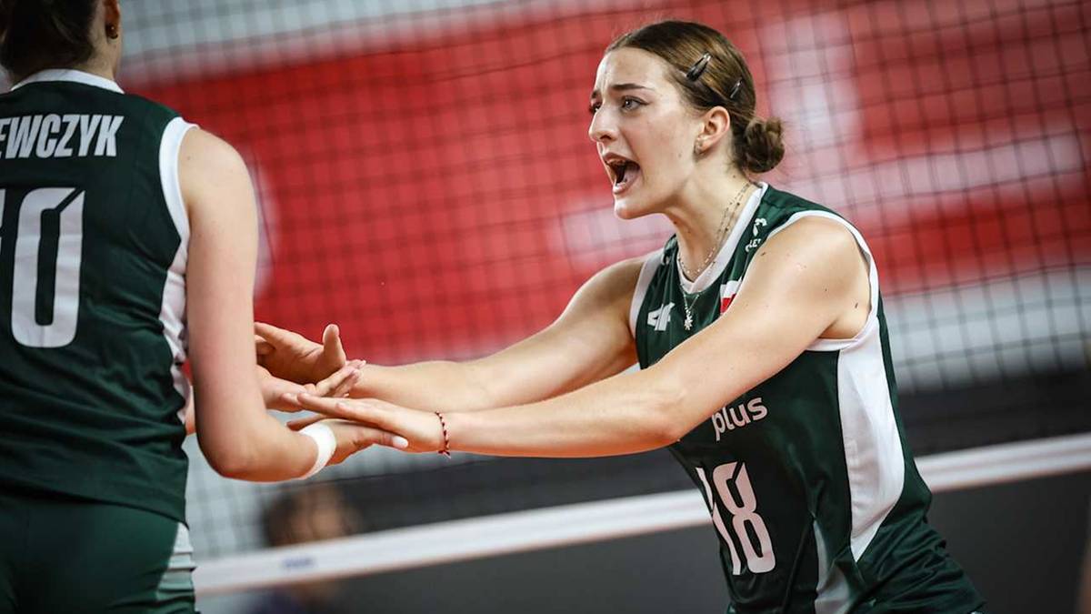 Dwie siatkarki w zielonych koszulkach z numerami na plecach wymieniają uwagi podczas meczu.