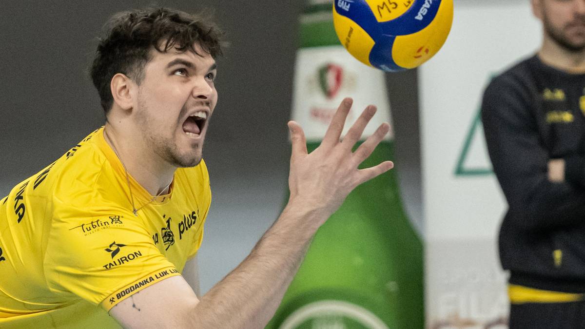 Siatkarz w żółtej koszulce z piłką do siatkówki w powietrzu.