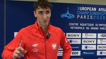 Ksawery Masiuk, polski pływak, w czerwonej bluzie sportowej z godłem Polski, wskazuje palcem i m&oacute;wi do kamery. W tle znajduje się baner "EUROPEAN AQUATIC CHAMPIONSHIPS PARIS 2026".