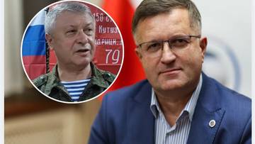 Zdjęcie przedstawia dw&oacute;ch mężczyzn, z kt&oacute;rych jeden jest w okularach i granatowej marynarce, a drugi w tle w stroju wojskowym.