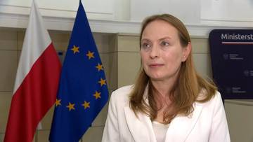Kobieta w białej marynarcze na tle flag Polski i UE.
