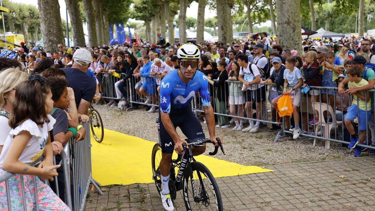 Kolarz w niebieskim stroju jedzie na rowerze wśród tłumu widzów.