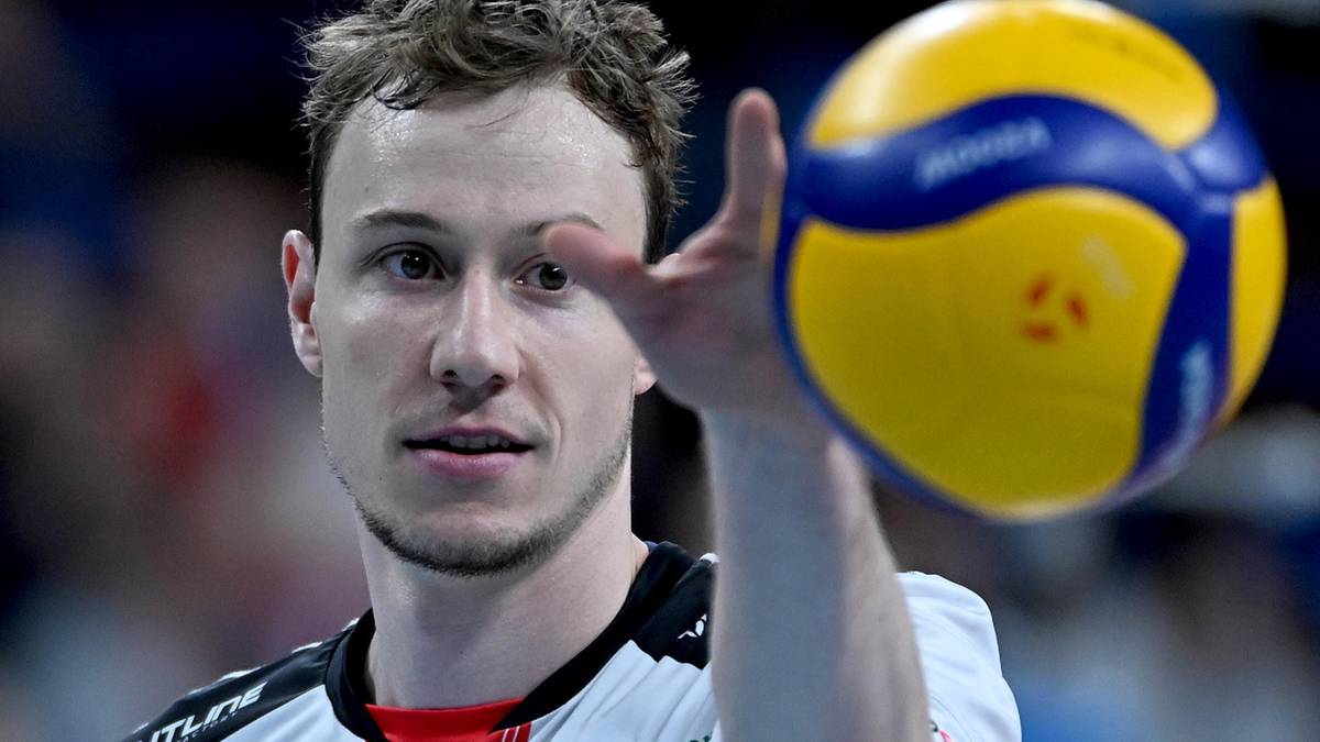 Siatkarz Sam Deroo trzyma w dłoni piłkę do siatkówki.