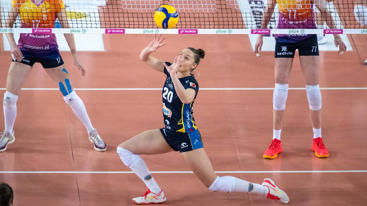 Siatkarka w granatowym stroju z numerem 20 wykonuje zagranie, obok niej inne zawodniczki na boisku siatkarskim.