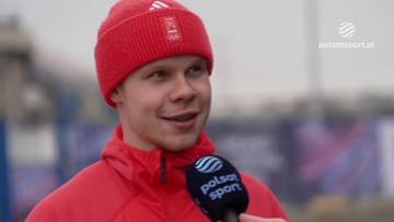 Michał Niewiński w czerwonej czapce i kurtce, udzielający wywiadu do mikrofonu Polsat Sport.