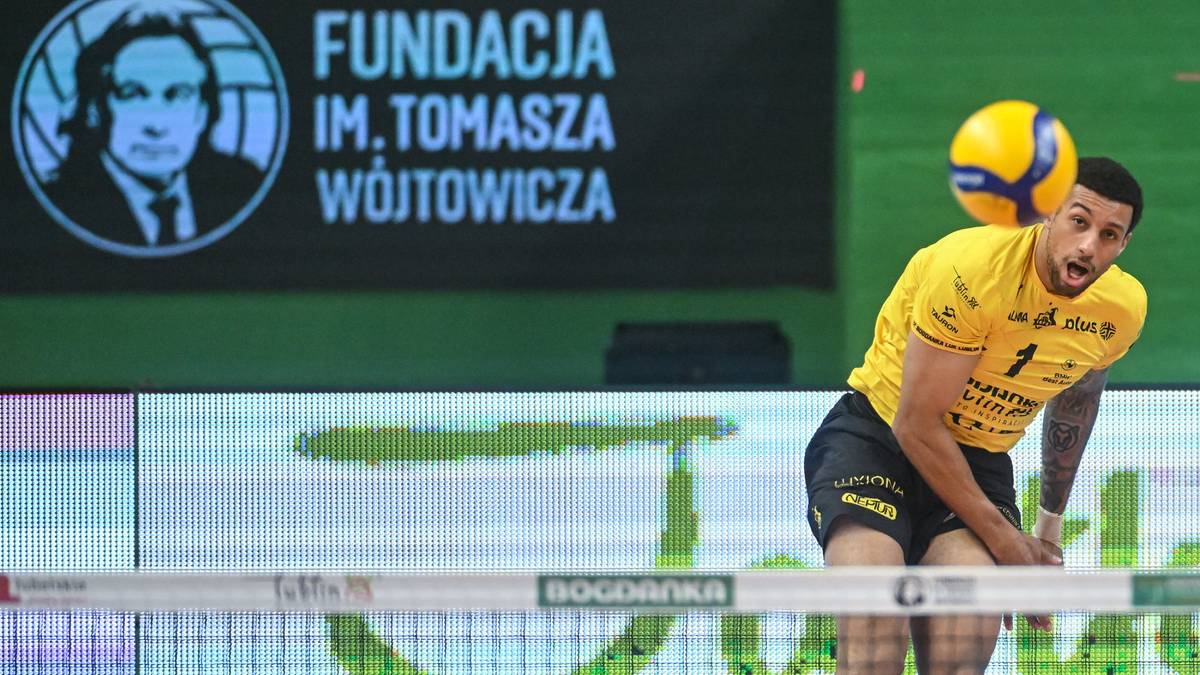 Siatkarz w żółtej koszulce z numerem 1 na plecach zagrywa piłkę.