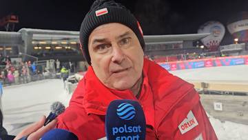 Mężczyzna w czerwonej kurtce i czapce z polską flagą, trzymający mikrofon Polsat Sport.