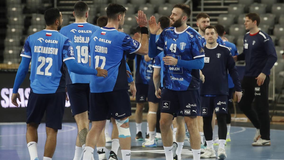 Drużyna piłkarzy ręcznych Orlen Wisły Płock w niebieskich strojach świętuje zwycięstwo, podając sobie ręce na parkiecie.
