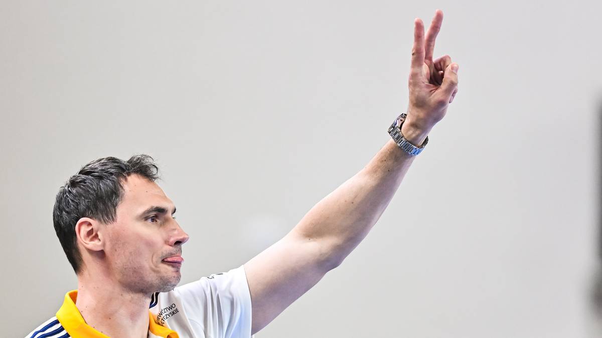 Krzysztof Lijewski unosi rękę z dwoma palcami skierowanymi w g&oacute;rę.