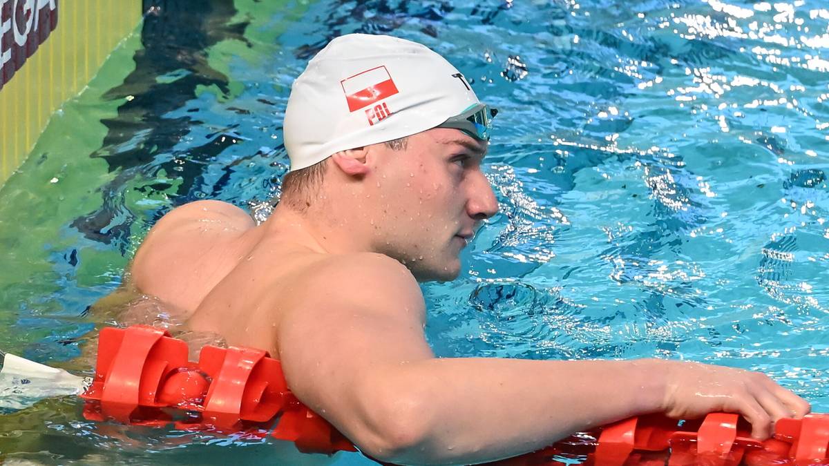 Pływak w czepku z polską flagą przy torze pływackim