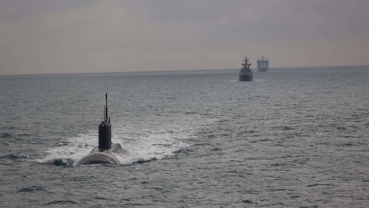 Rosyjski okręt podwodny płynący po powierzchni morza, z widocznym peryskopem i śladami fal.