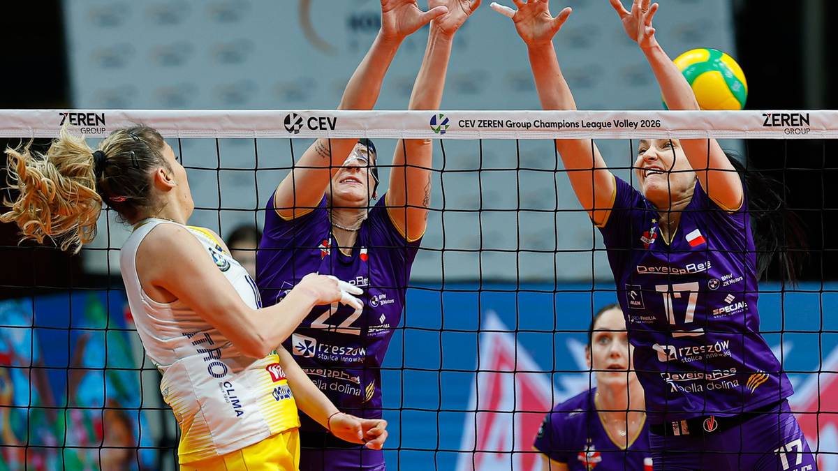 Siatkarki w akcji przy siatce, jedna z nich pr&oacute;buje zablokować atak przeciwniczki.