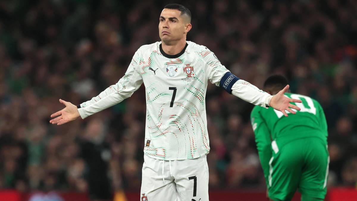Piłkarz Cristiano Ronaldo w białej koszulce z numerem 7, z rozłożonymi ramionami, na boisku piłkarskim.