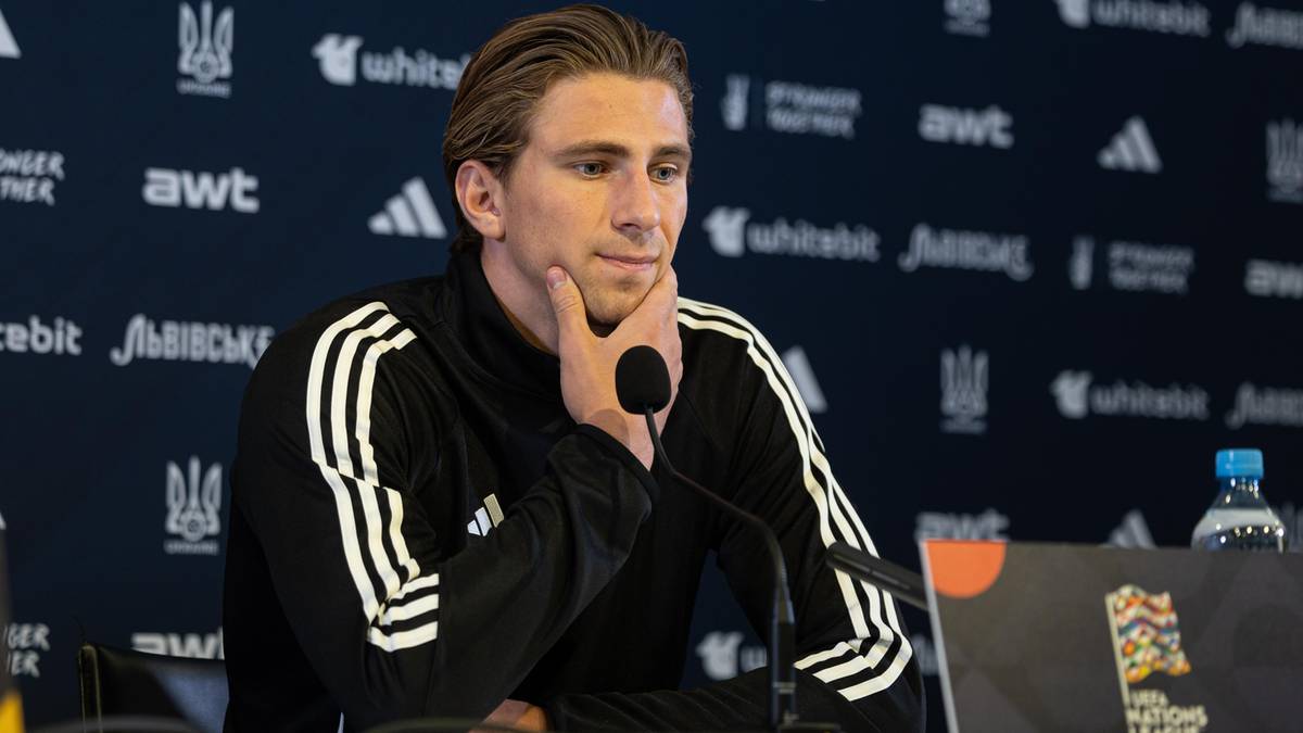 Mężczyzna opiera podbródek na dłoni, siedząc przy stole konferencyjnym.