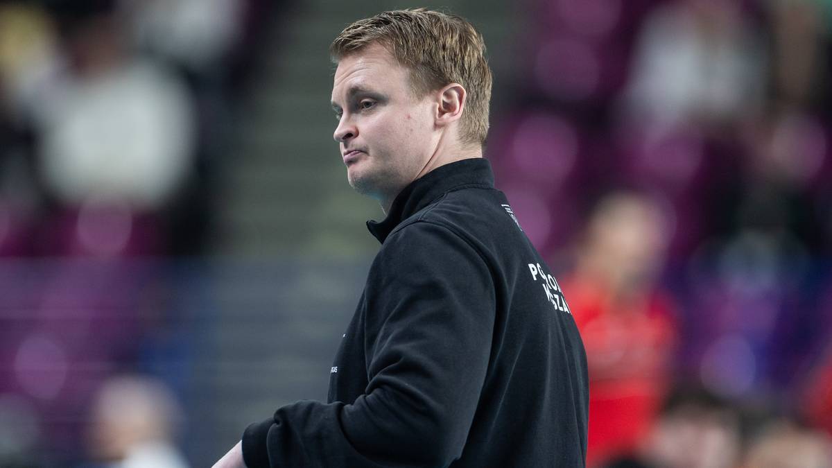 Mężczyzna w czarnej bluzie z kołnierzem, patrzy w bok z lekkim zamyśleniem.