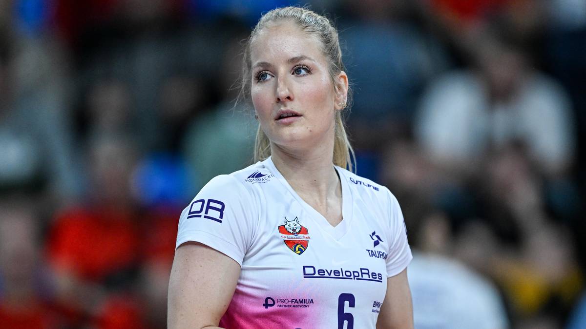 Portret młodej kobiety w białej koszulce sportowej z widocznymi emblematami i numerem 6.