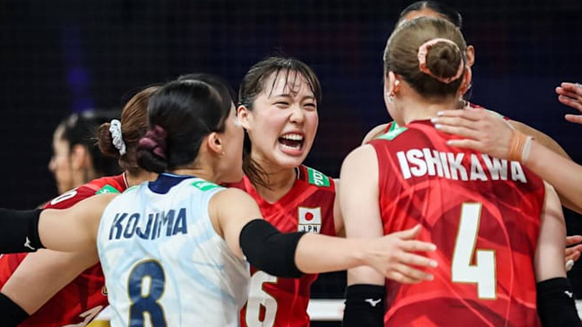 Kilka zawodniczek z japońskiej drużyny siatkarskiej w czerwonych strojach sportowych, świętujących zwycięstwo lub ważny moment w meczu. Jedna z nich otwiera usta w okrzyku radości.