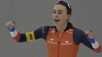 Łyżwiarka szybka w pomarańczowo-szarym stroju cieszy się ze zwycięstwa, podnosząc pięści do góry.