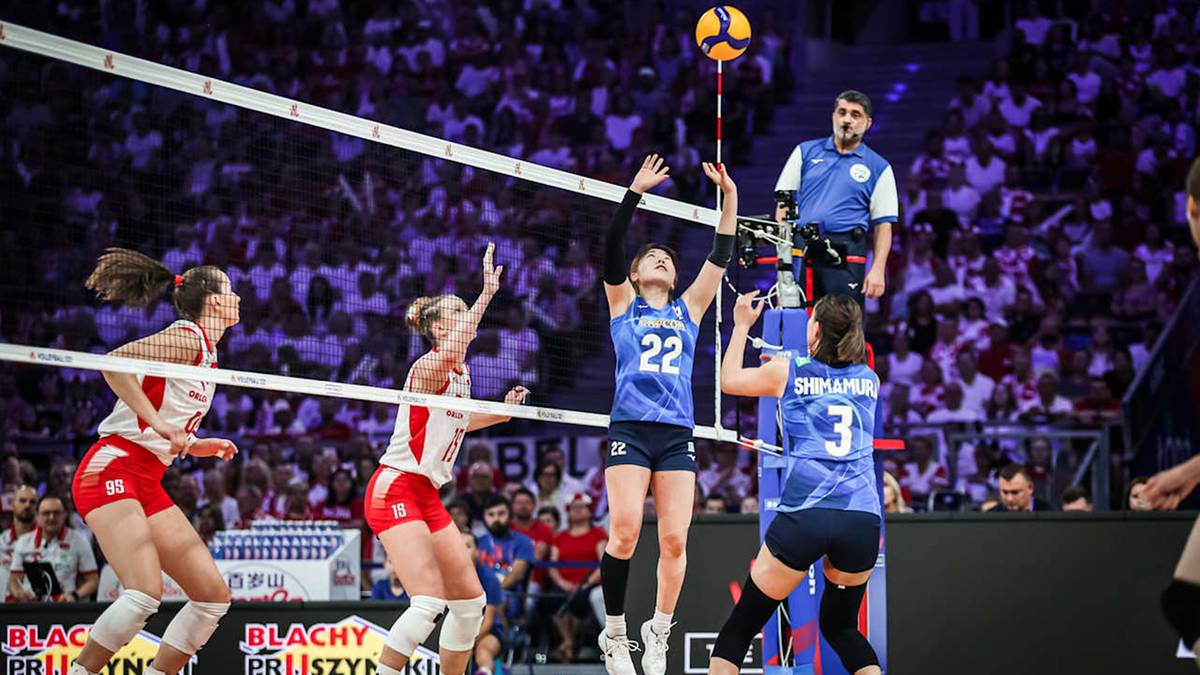 Siatkarka w niebieskim stroju z numerem 22 na plecach wyskakuje do zagrywki nad siatką podczas meczu siatk&oacute;wki. Po drugiej stronie siatki po lewej stronie widać siatkarki w czerwonych strojach.