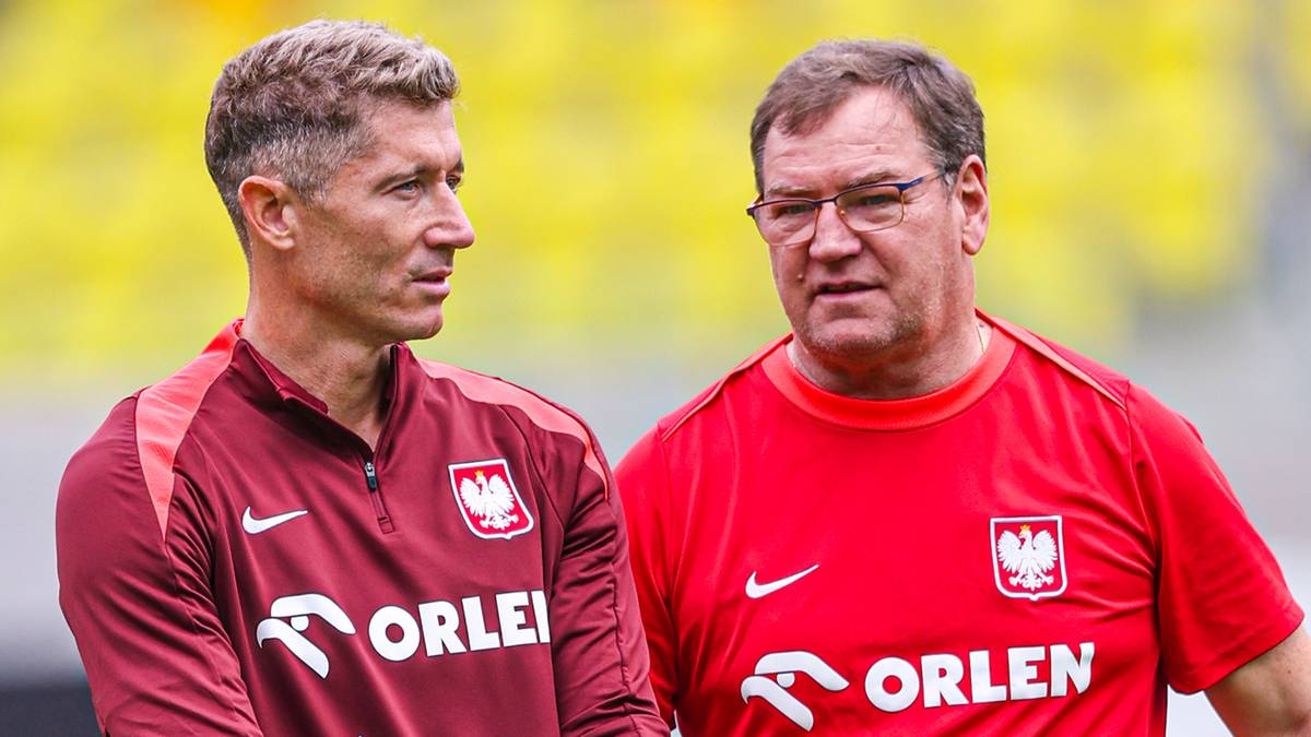 Dw&oacute;ch mężczyzn w strojach sportowych reprezentacji Polski, jeden z nich trzyma piłkę.