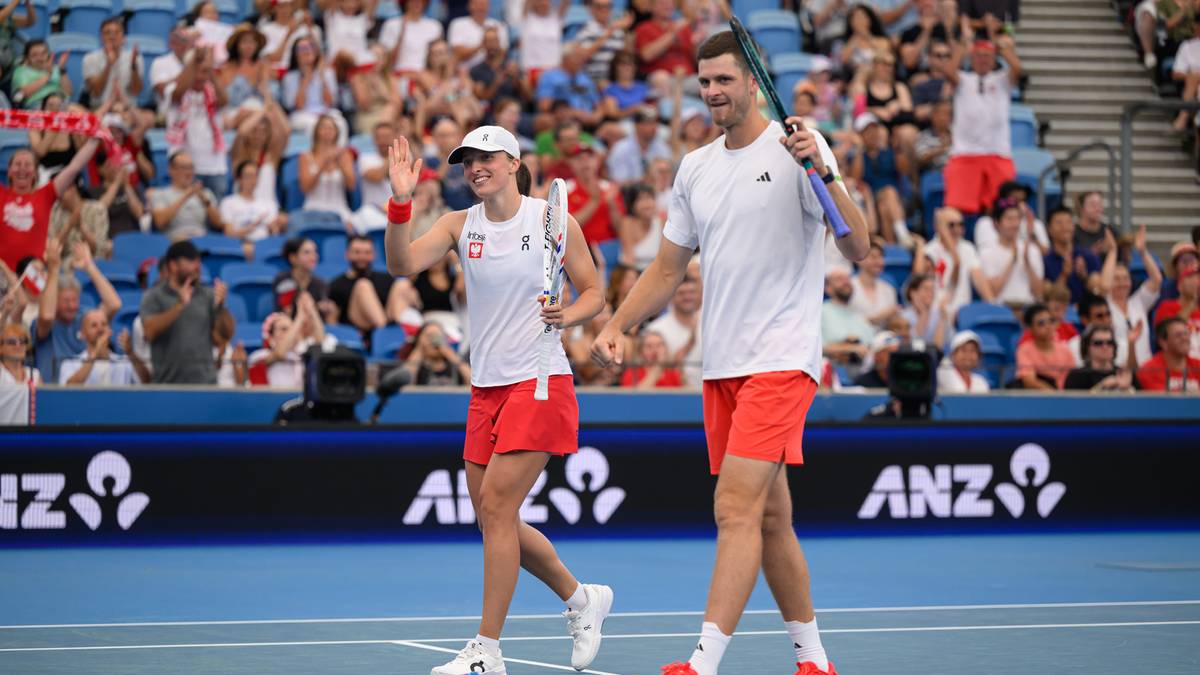 Tenisistka i tenisista w strojach reprezentacji Polski na korcie tenisowym.