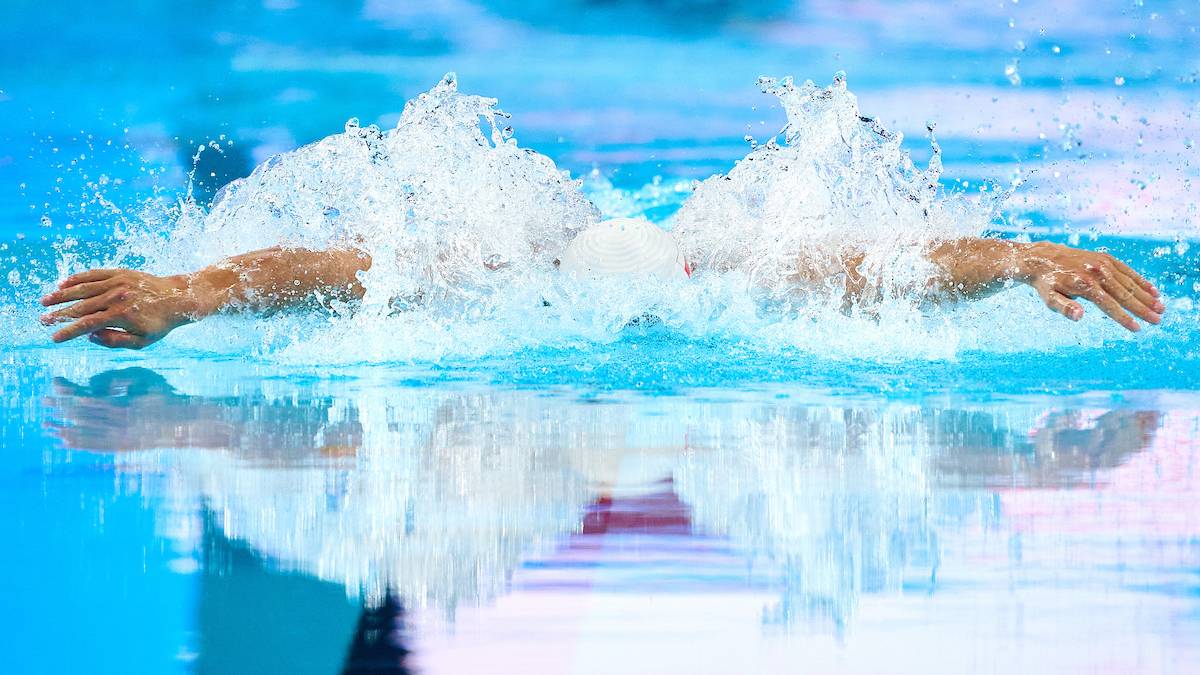 Pływak wykonujący styl motylkowy, z rozbryzgami wody wokół głowy.