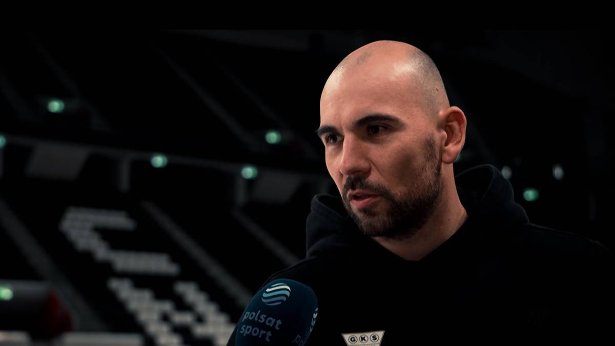 Portret Jakuba Grutha z mikrofonem Polsat Sport na tle stadionu.