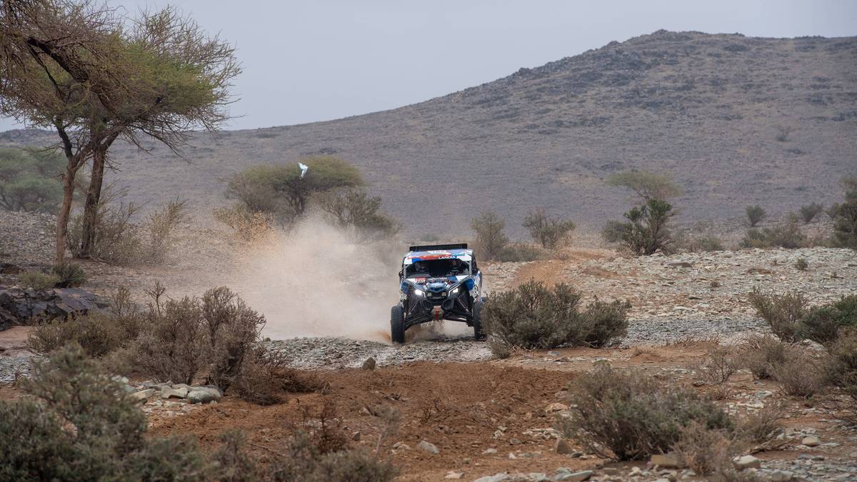 Samochód terenowy poruszający się po kamienistej, zapylonej drodze na pustyni.