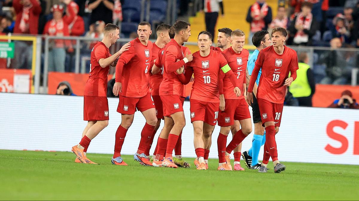 Drużyna piłkarska w czerwonych strojach świętuje zdobycie bramki.