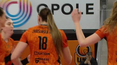 Siatkarka w pomarańczowej koszulce z numerem 18 na plecach, odwr&oacute;cona tyłem do widza, świętująca z innymi zawodniczkami. W tle logo "OPOLE".