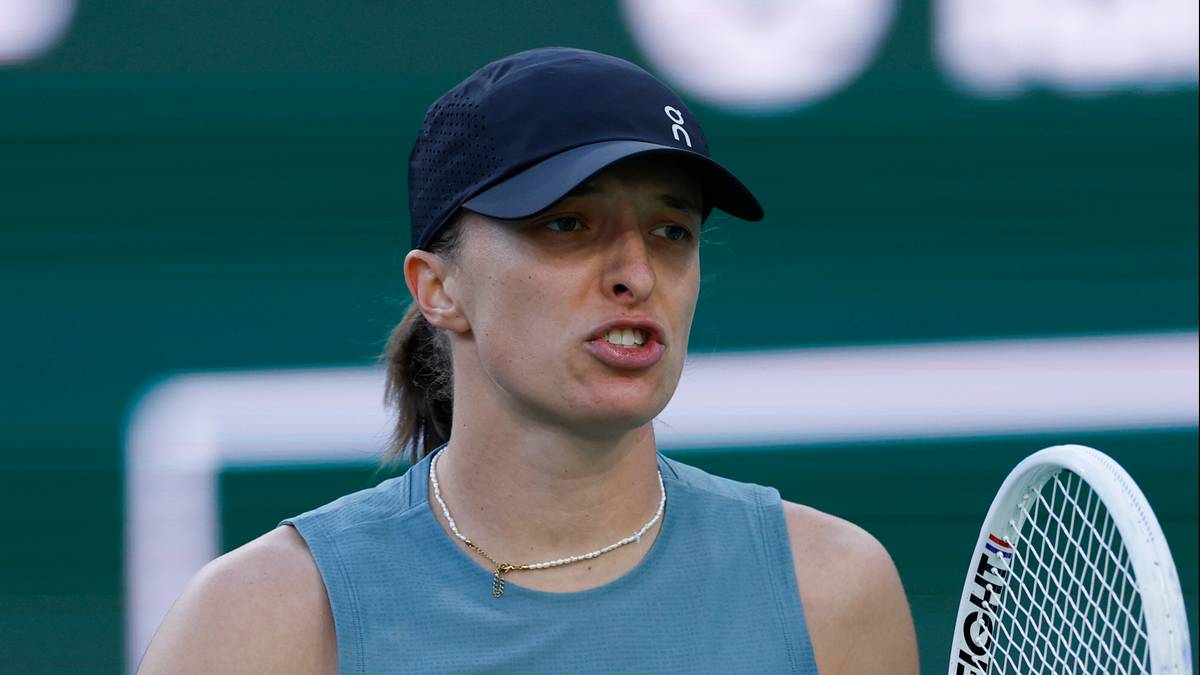 Iga Świątek podczas meczu tenisowego, w czapce i sportowym stroju, trzyma rakietę.