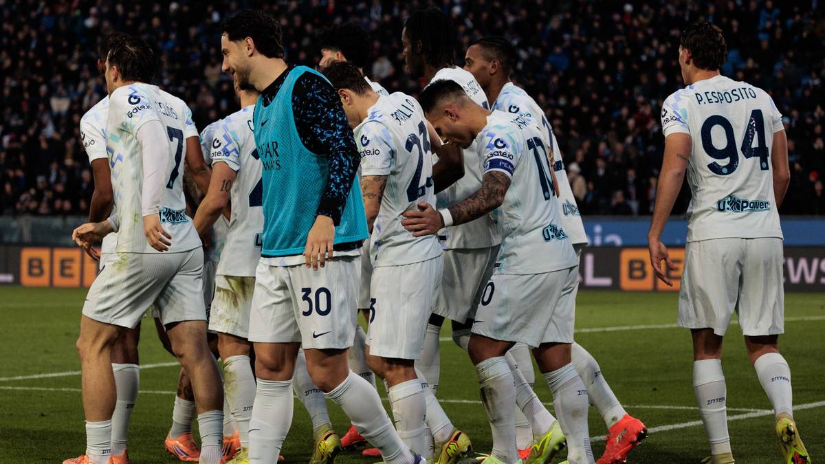 Piłkarze w białych strojach z niebieskimi elementami świętują na boisku piłkarskim.