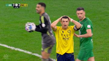 Piłkarz w ż&oacute;łtej koszulce trzyma się za głowę, wyrażając frustrację, podczas meczu piłki nożnej. Obok niego stoją dwaj inni zawodnicy.