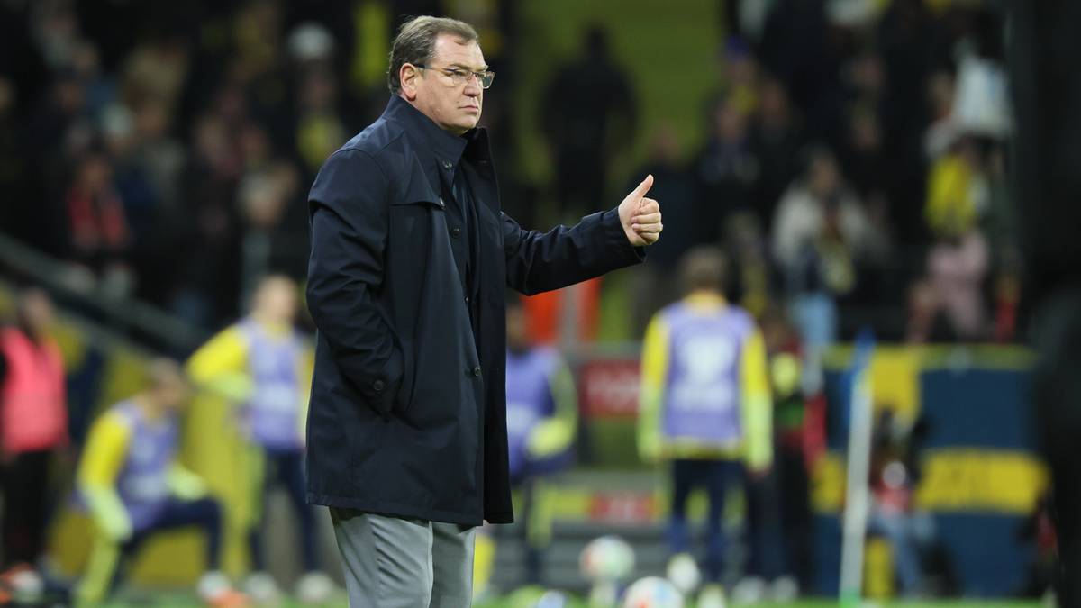 Trener reprezentacji Polski, Jan Urban, pokazuje kciuk w g&oacute;rę na tle stadionu i kibic&oacute;w.