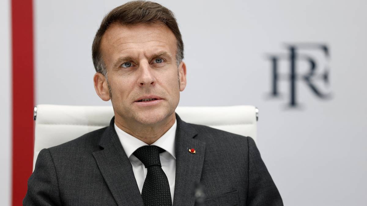Emmanuel Macron w garniturze i krawacie, siedzący podczas spotkania.