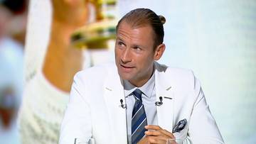 Łukasz Kubot w białym garniturze i krawacie, siedzi przy mikrofonie.