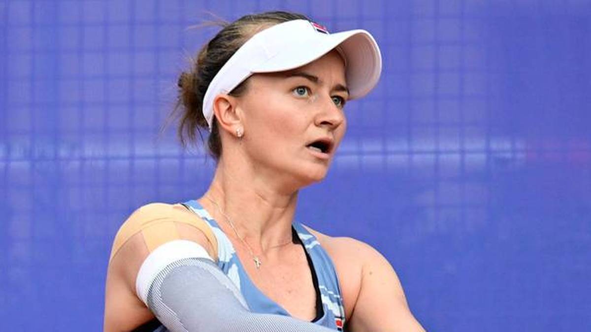 Zdjęcie przedstawia tenisistkę w białej czapce z daszkiem, skupioną na grze.