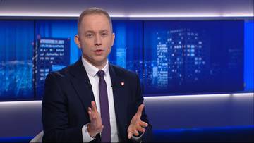 Cezary Tomczyk w garniturze i krawacie przemawia w studiu telewizyjnym.