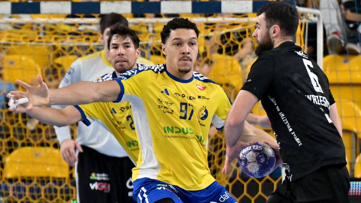 Piłkarz ręczny w żółtej koszulce z numerem 97 próbuje rzucić piłkę, broniony przez zawodnika w czarnej koszulce.