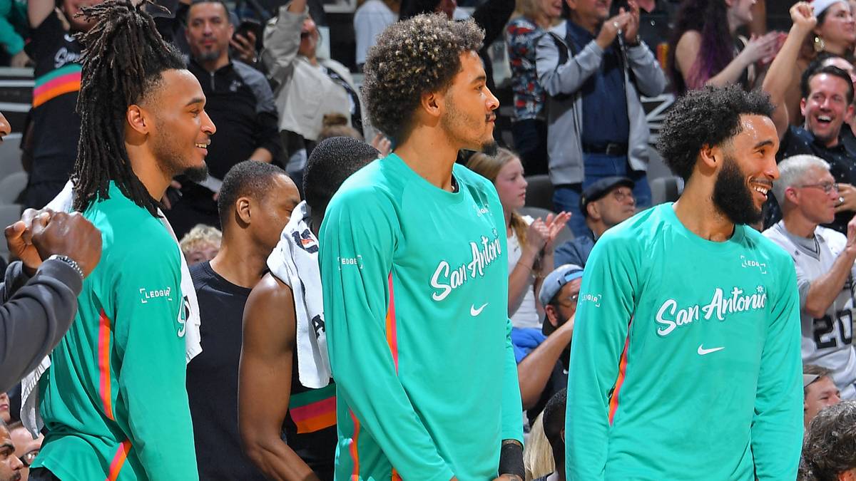 Gracze San Antonio Spurs siedzą na ławce rezerwowych podczas meczu.