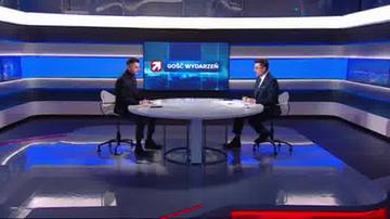 Dw&oacute;ch mężczyzn siedzi przy stole w studiu telewizyjnym, na ekranie za nimi widnieje logo programu "Gość Wydarzeń".