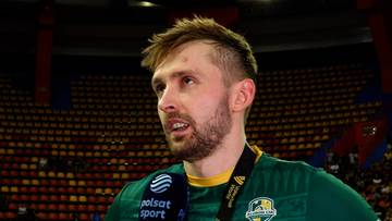 Portret Mateusza Bienka, polskiego siatkarza, w zielonej koszulce z widoczną opaską z logo Polsat Sport. Tło stanowi trybuna stadionu wypełniona widzami.