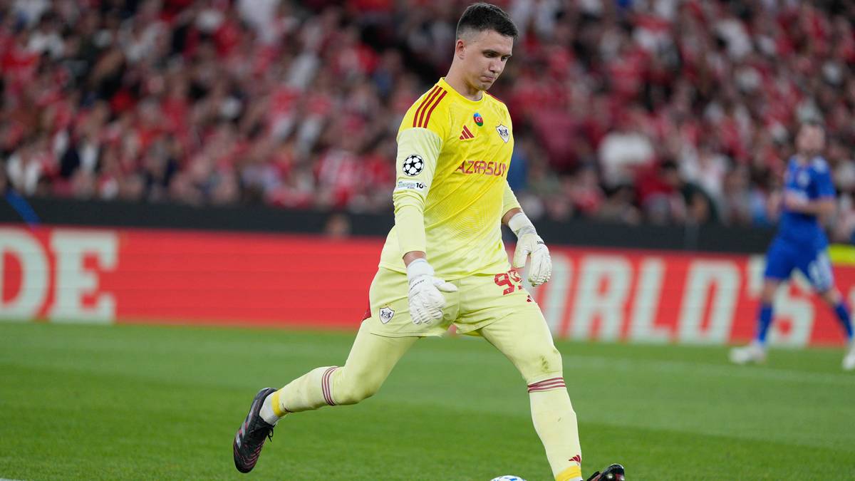 Bramkarz w żółtym stroju w trakcie akcji na boisku.