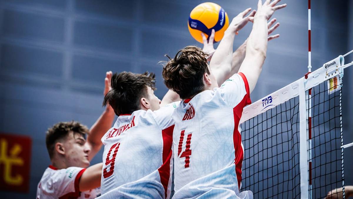 Siatkarze Polski w akcji podczas meczu, jeden z zawodników wykonuje atak, blokując piłkę nad siatką.