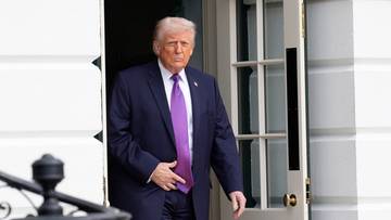 Donald Trump w garniturze wychodzi przez drzwi.