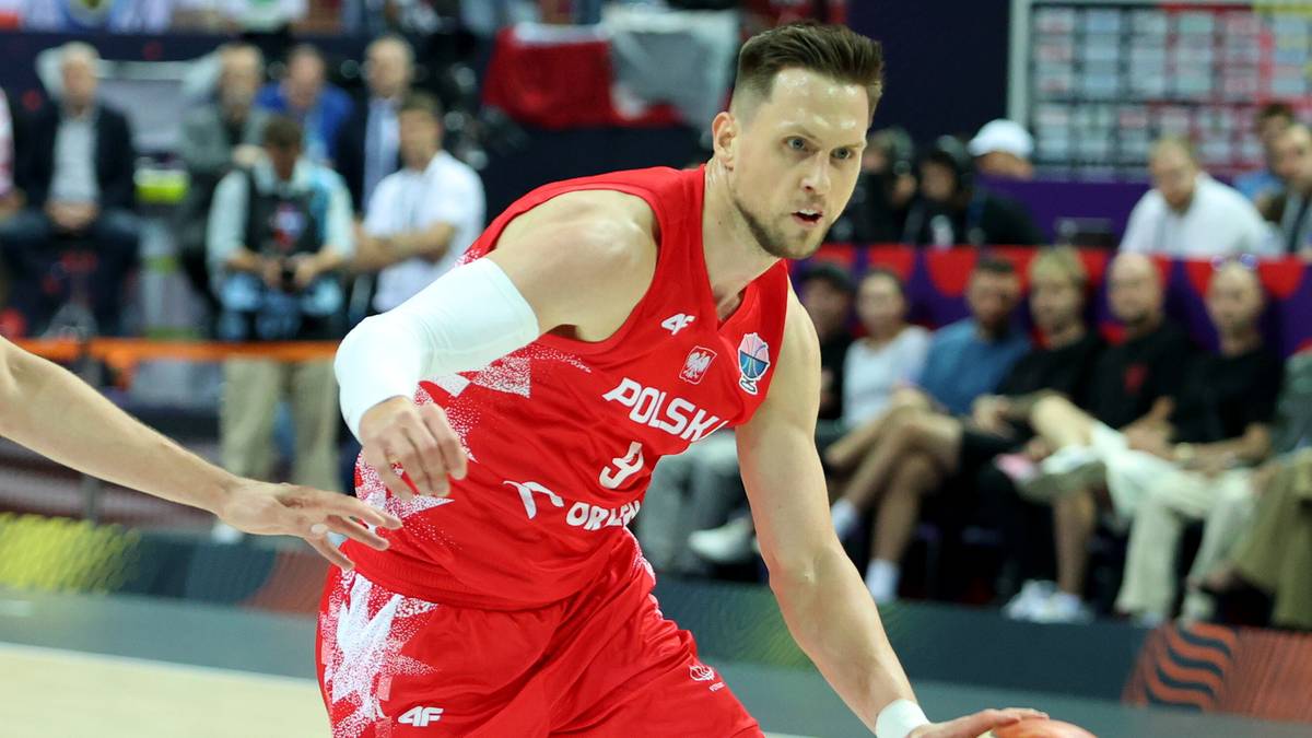 Gracz w czerwonej koszulce z napisem POLSKA z piłką do koszykówki w ręku, podczas meczu.