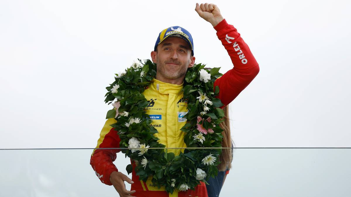 Robert Kubica na podium z wieńcem laurowym na szyi.