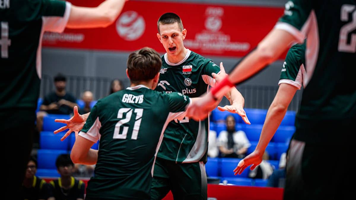 Dwóch siatkarzy w zielonych strojach z białymi numerami na plecach celebruje zdobycie punktu, podając sobie ręce na boisku siatkarskim.