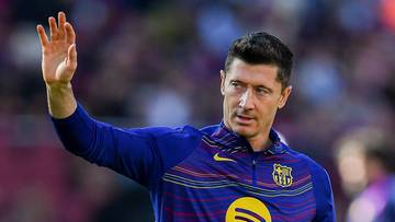 Robert Lewandowski pozdrawia kibiców na boisku piłkarskim.